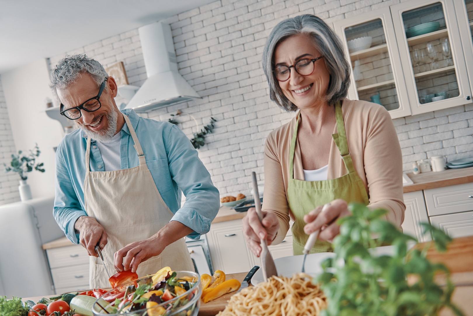 Older man and woman smiling and cooking a healthy meal at home Older man and woman smiling and cooking a healthy meal at home