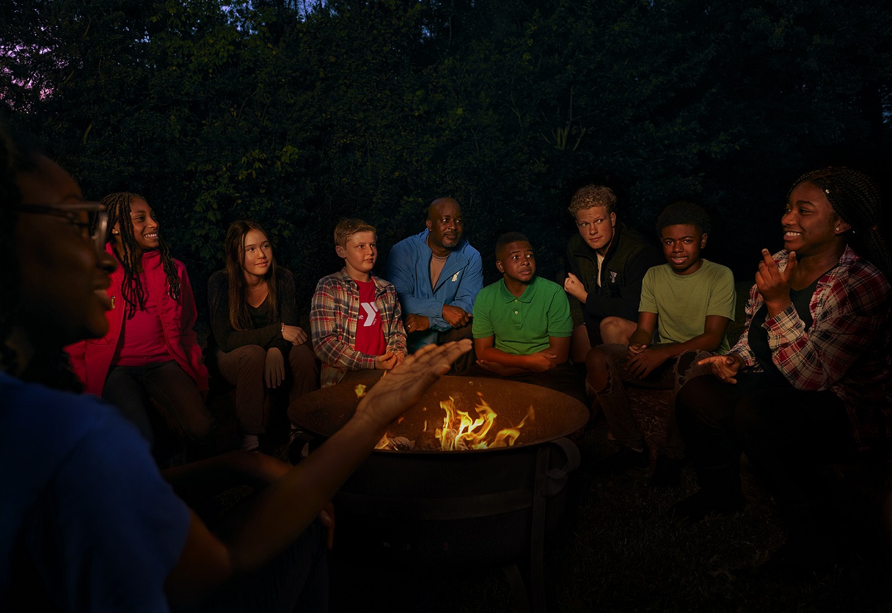 Campers and counselors sit around a campfire at night Campers and counselors sit around a campfire at night