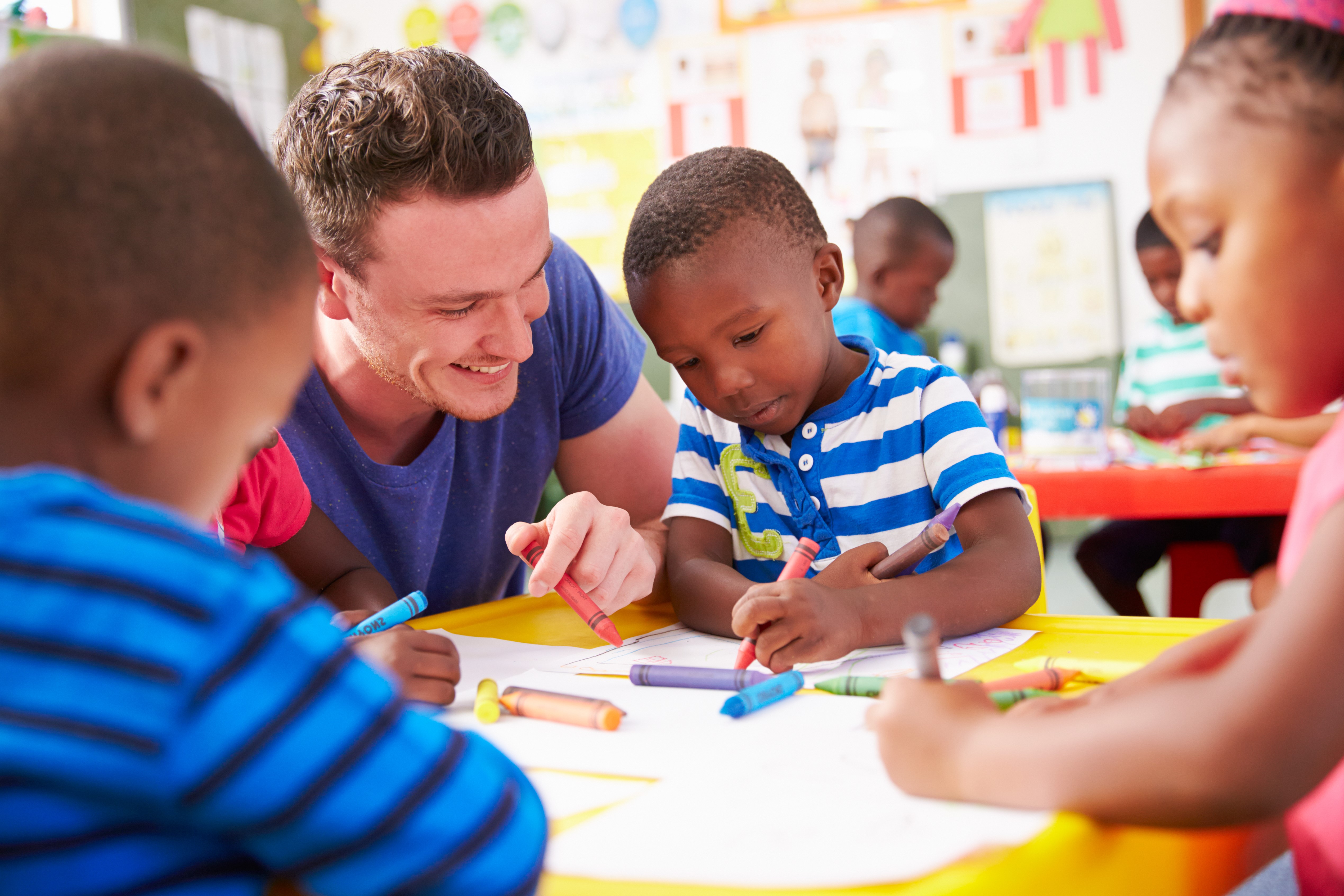 YMCA staff coloring with kids at YMCA child care program YMCA staff coloring with kids at YMCA child care program