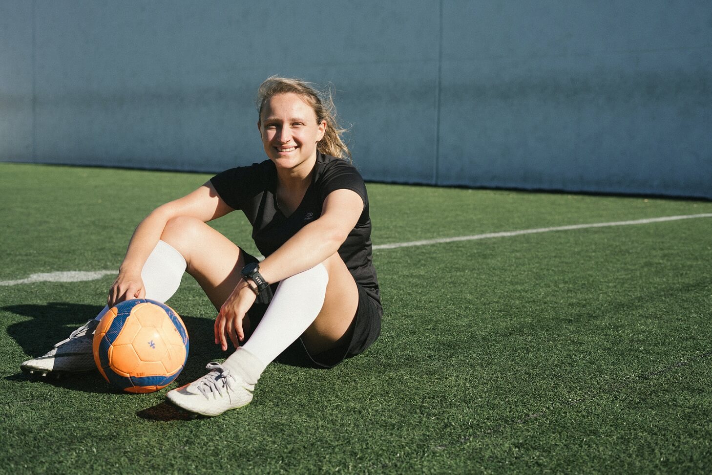 Woman sitting on a soccer field smiling Woman sitting on a soccer field smiling