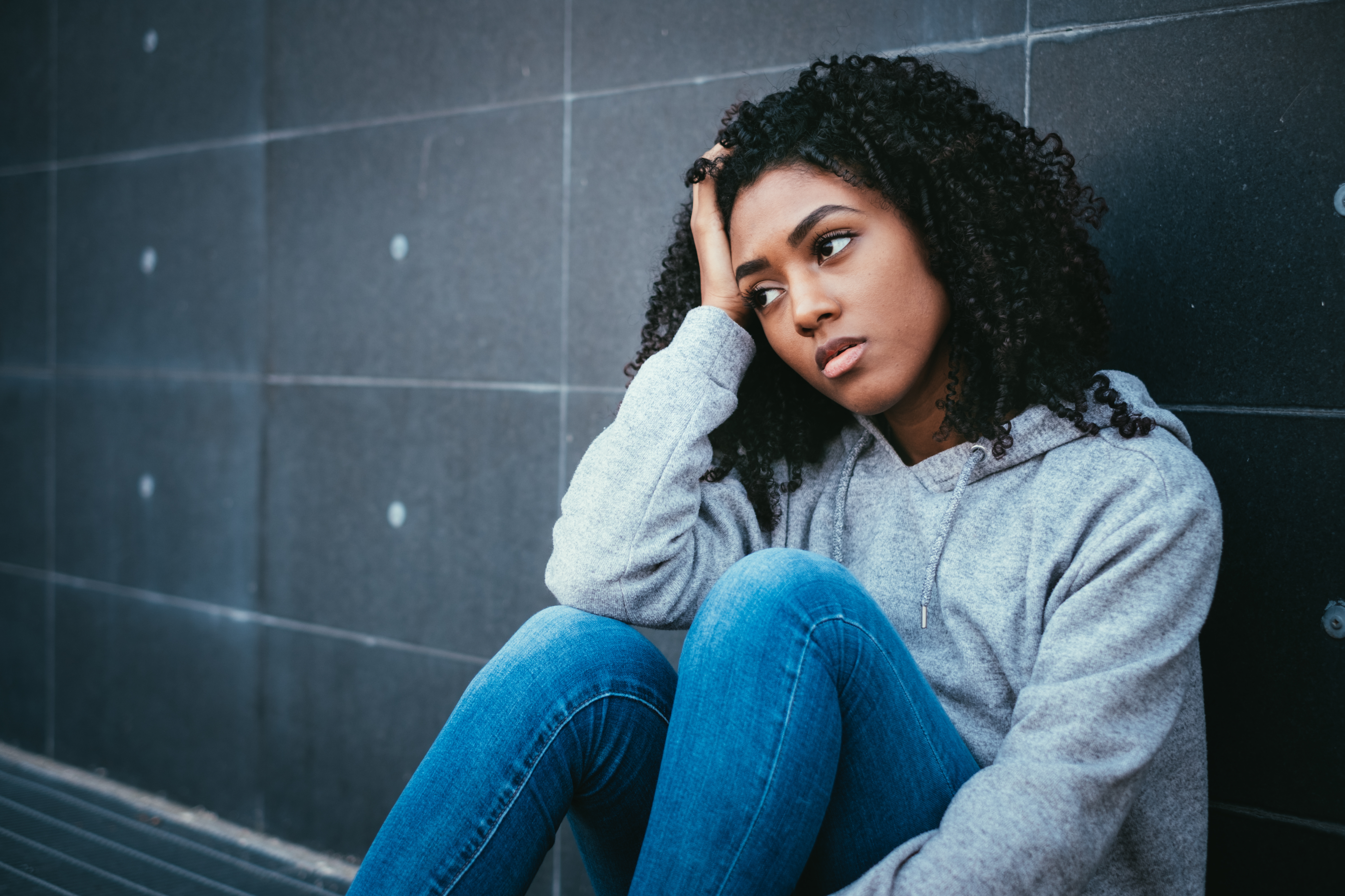 Teen sitting on the floor looking forlorn Teen sitting on the floor looking forlorn