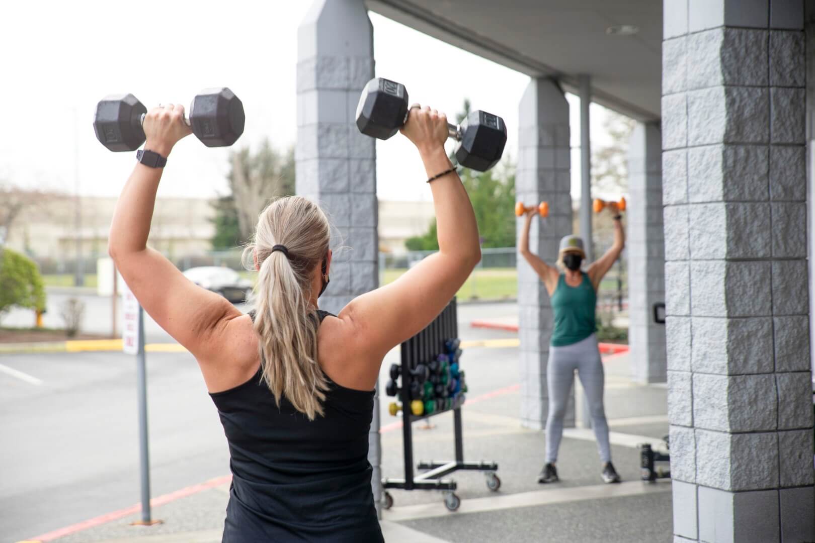 Woman shoulder pressing dumbbells at strength class Woman shoulder pressing dumbbells at strength class