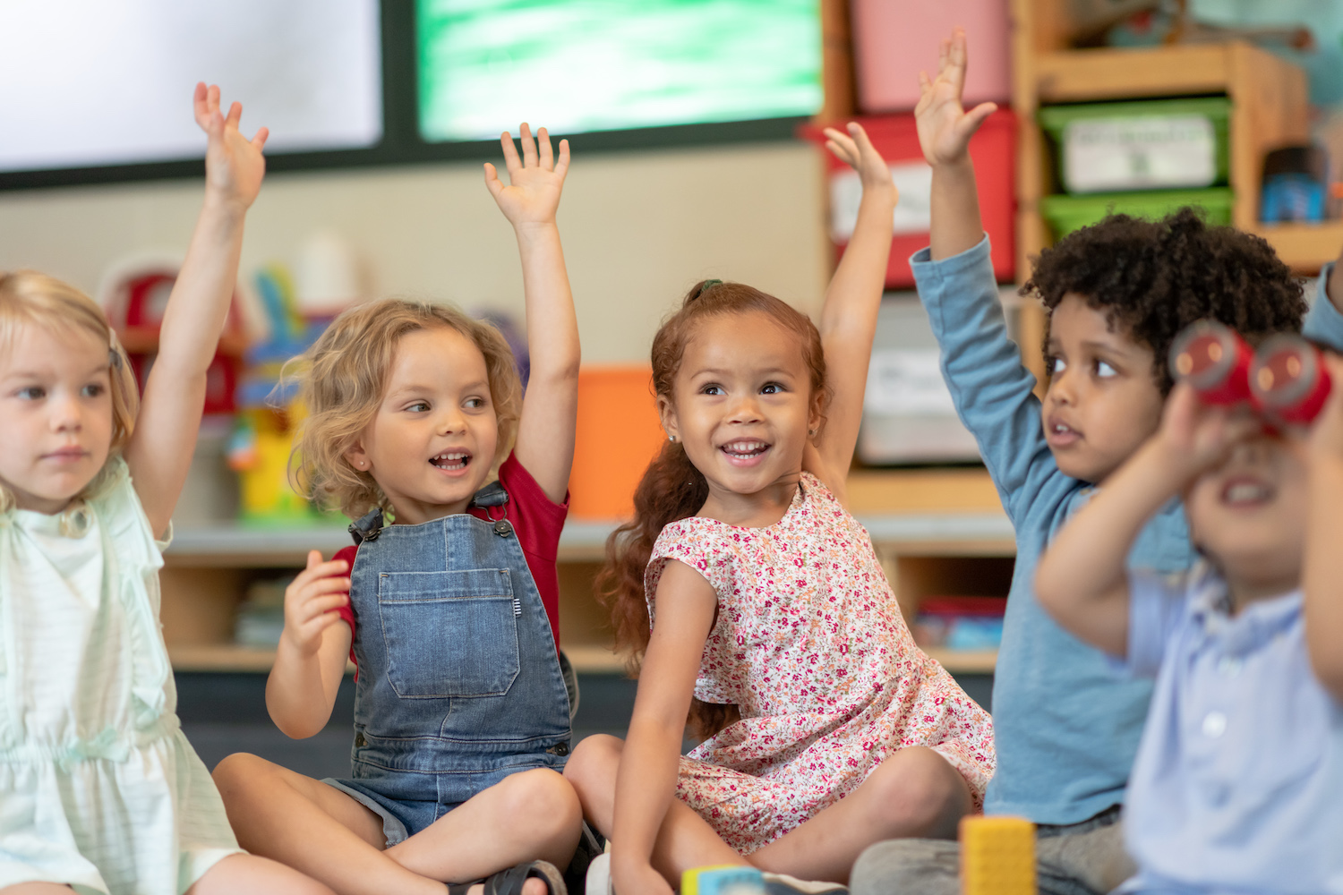 Kids raising their hands in YMCA child care program Kids raising their hands in YMCA child care program