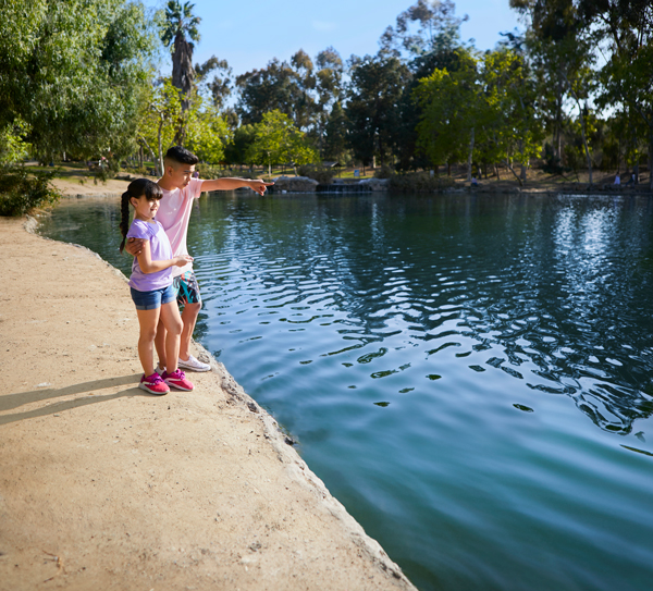 Young kids hanging out in a park by a lake Young kids hanging out in a park by a lake