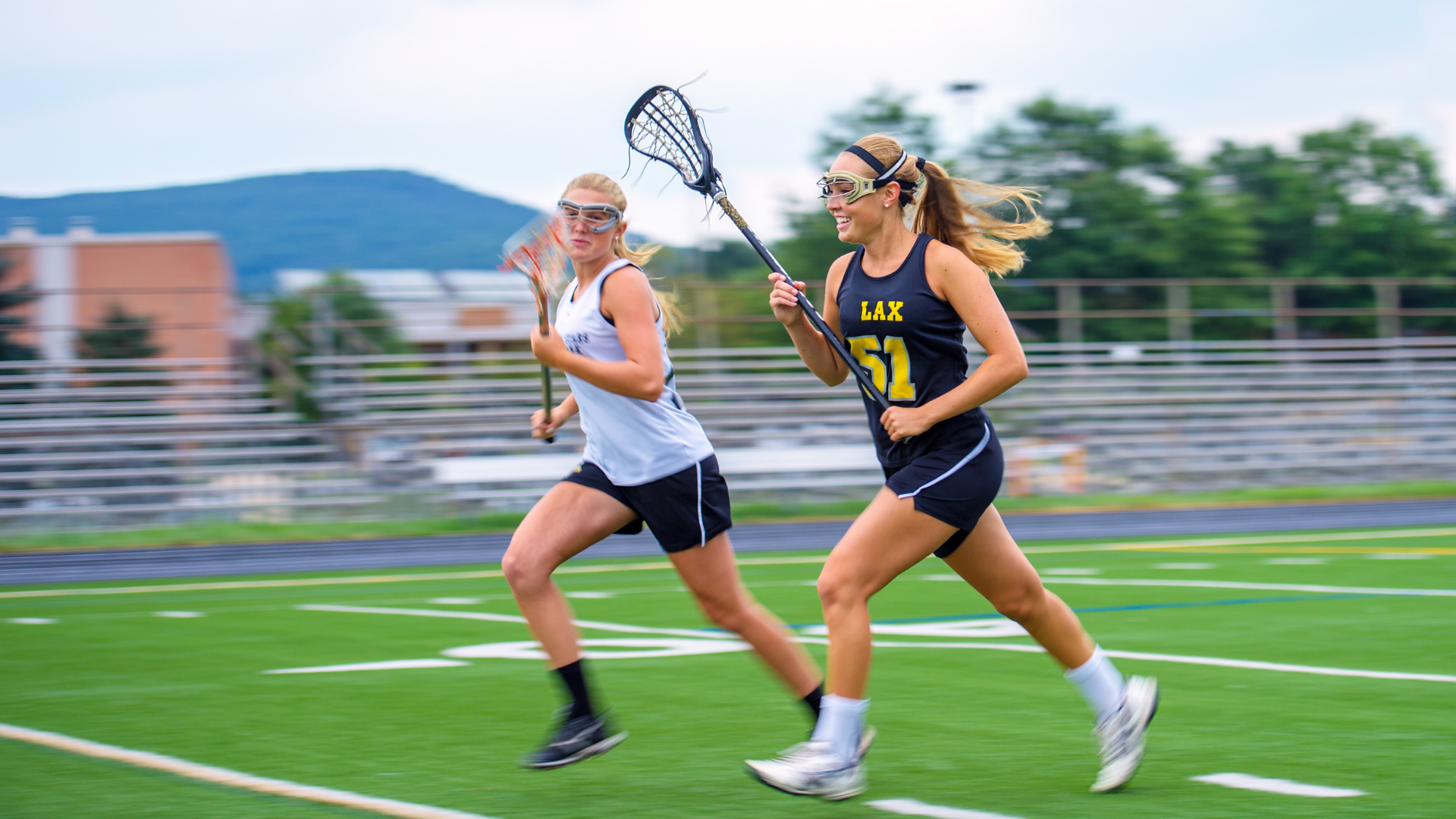 Teens running across a lacrosse field Teens running across a lacrosse field