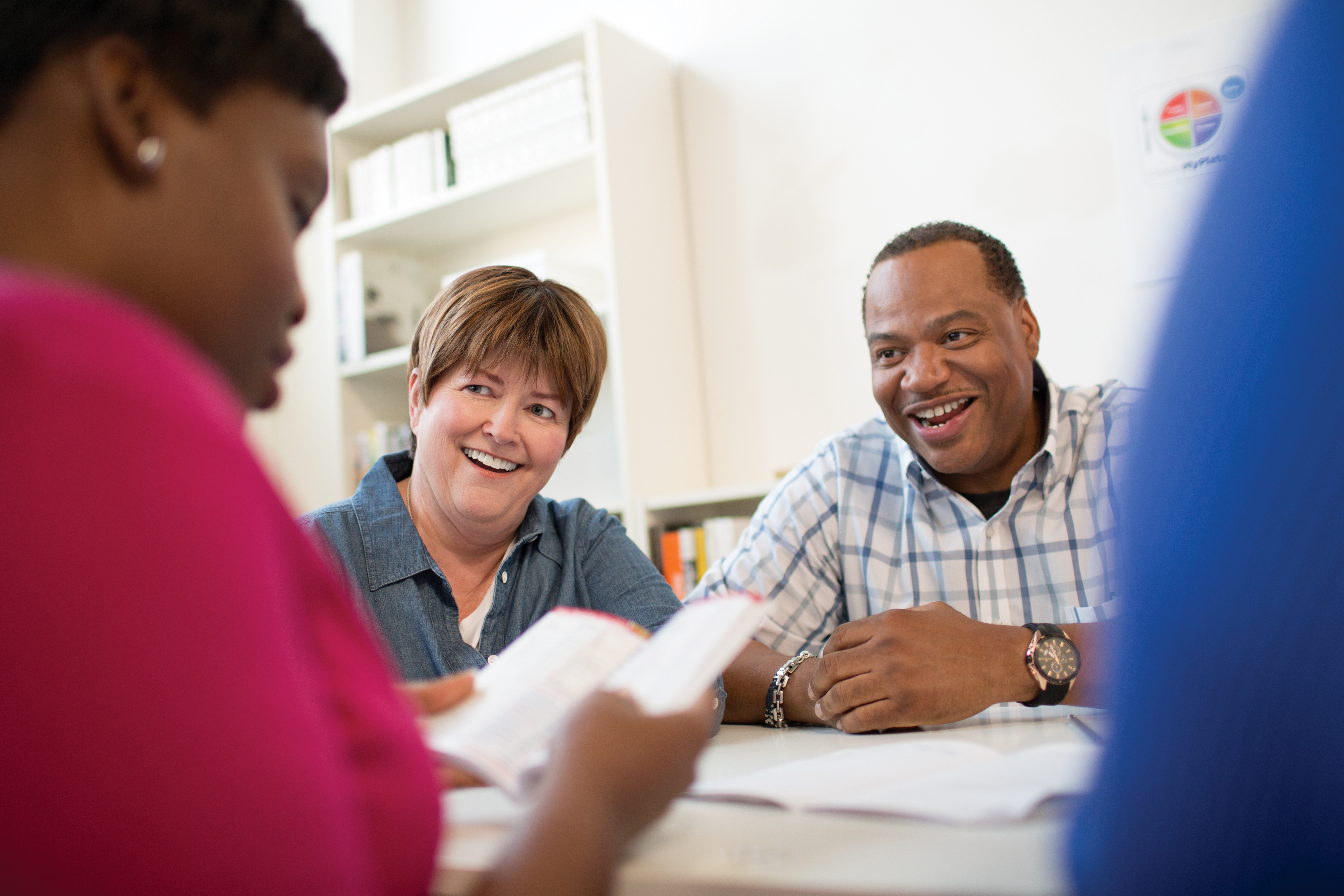 Man and woman smiling as they review information with instructor Man and woman smiling as they review information with instructor