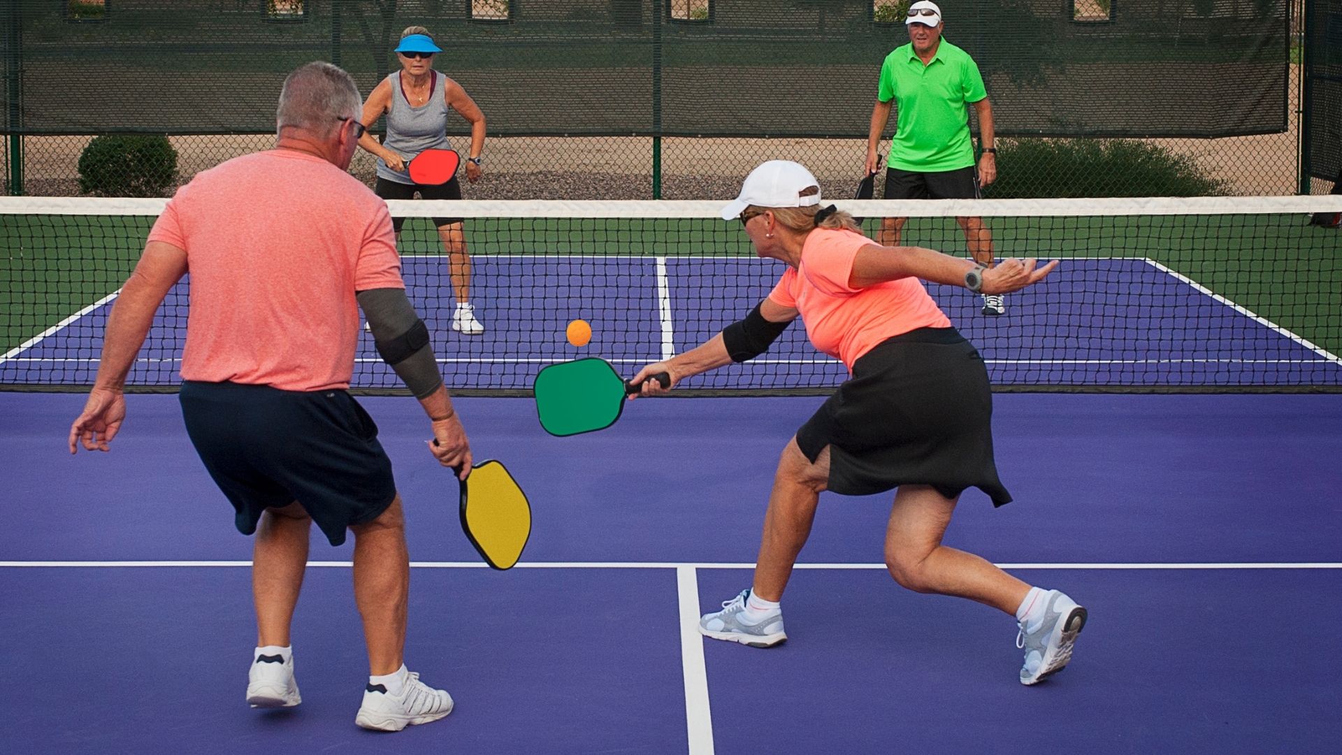 Group of four older adults playing pickleball outdoors Group of four older adults playing pickleball outdoors