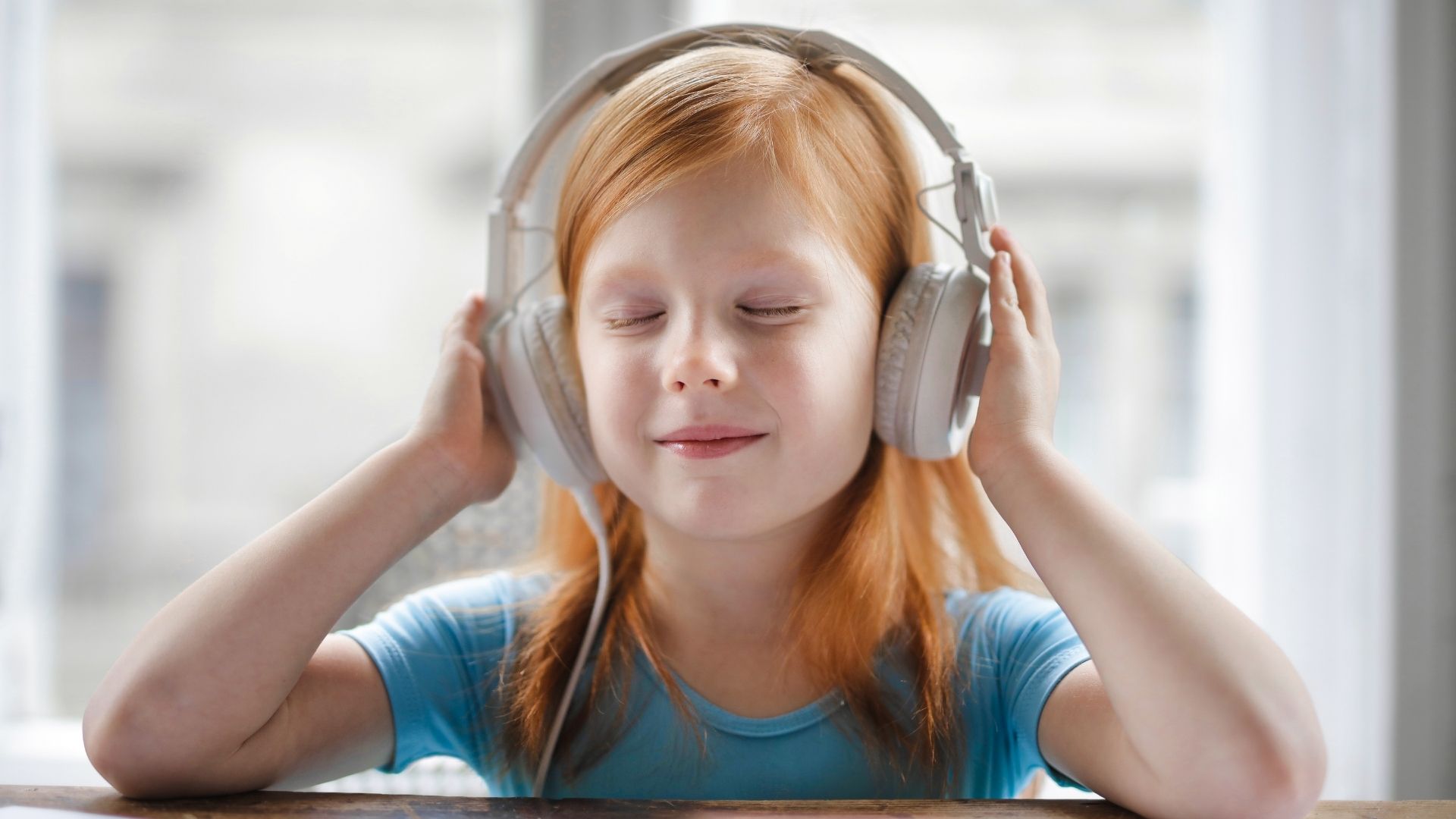 Young girl smiling with eyes closed using headphones to listen to music Young girl smiling with eyes closed using headphones to listen to music