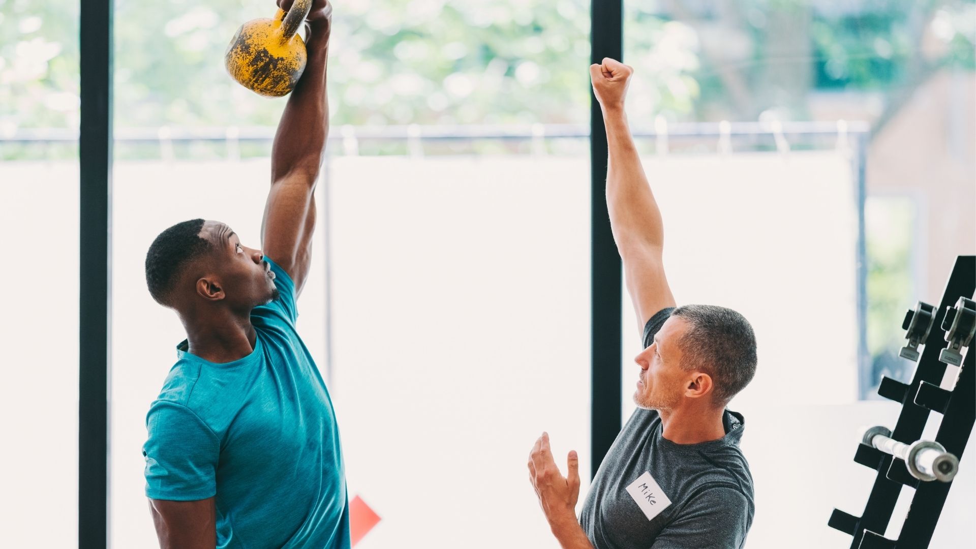 Male trainer teaching male client how to lift kettlebell Male trainer teaching male client how to lift kettlebell