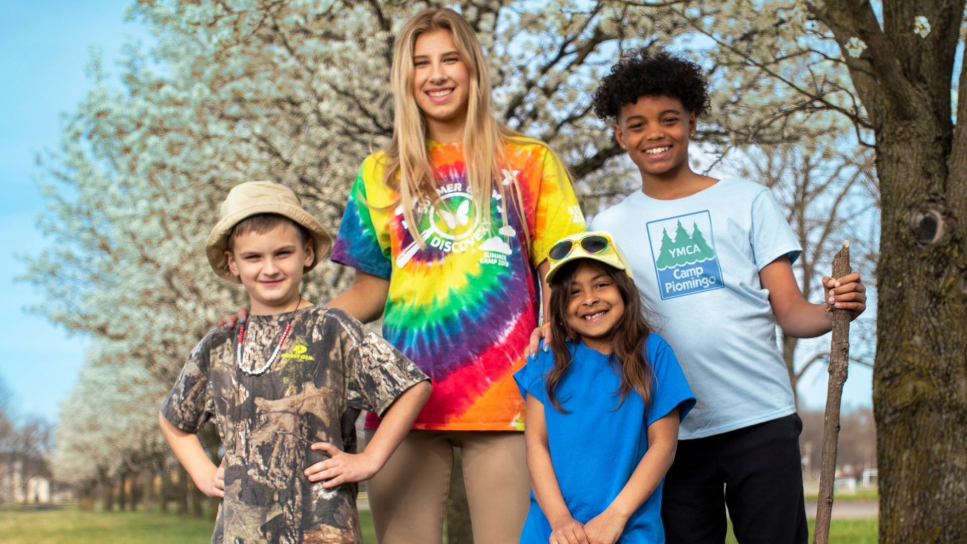 Camp counselor standing outdoors with 3 smiling campers Camp counselor standing outdoors with 3 smiling campers