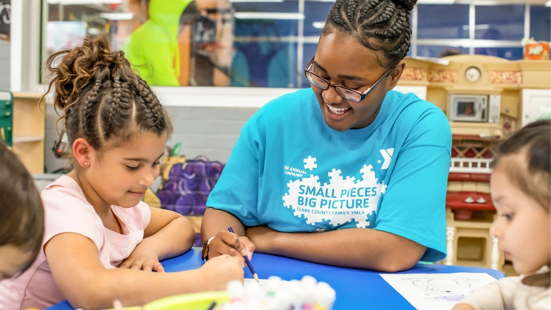 Kids' Club staff member doing crafts with happy young children Kids' Club staff member doing crafts with happy young children