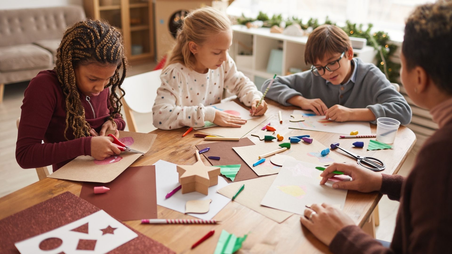 2 girls and a boy sitting a table doing crafts 2 girls and a boy sitting a table doing crafts