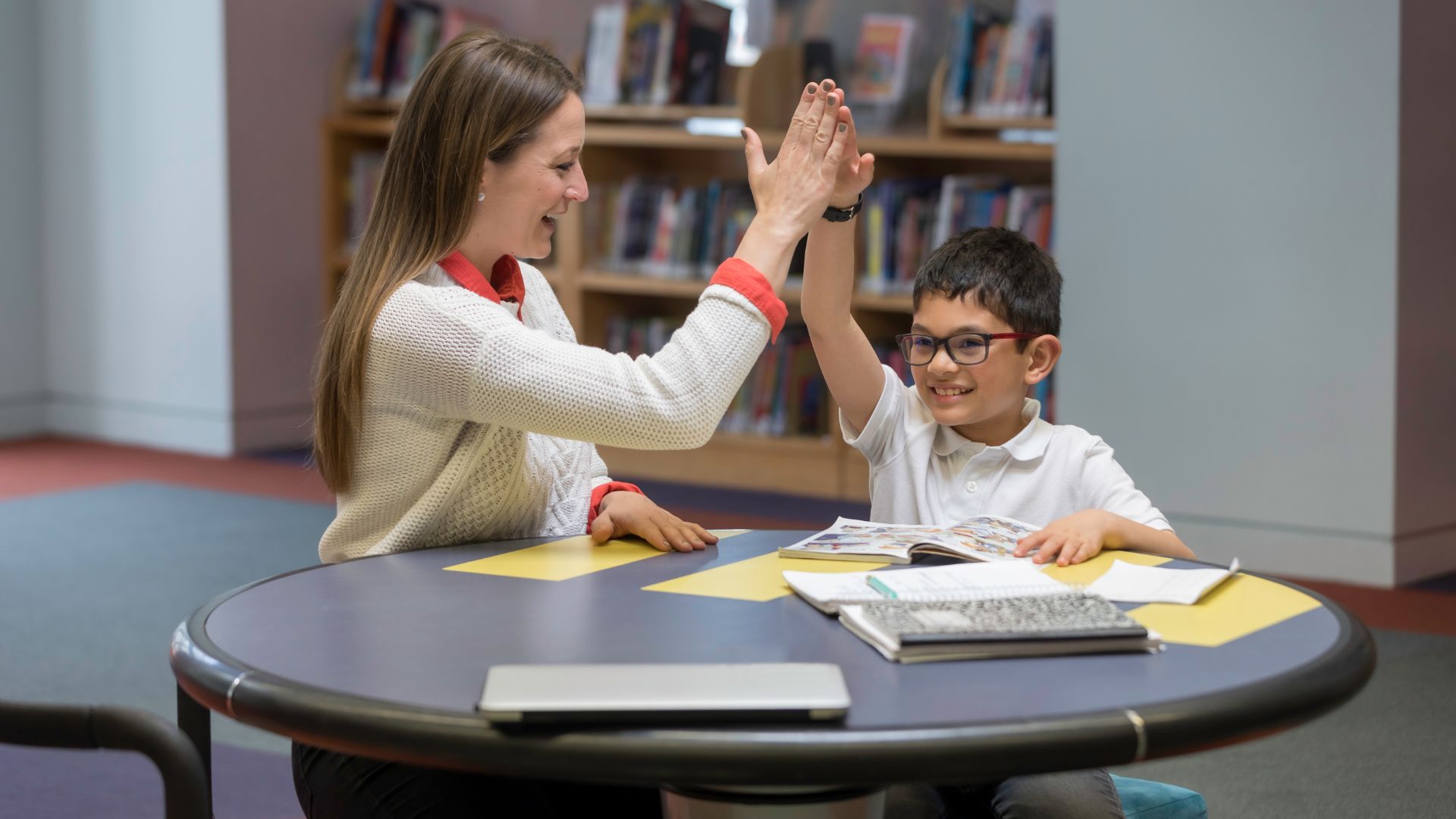 Tutor high fiving with young student after completing session Tutor high fiving with young student after completing session