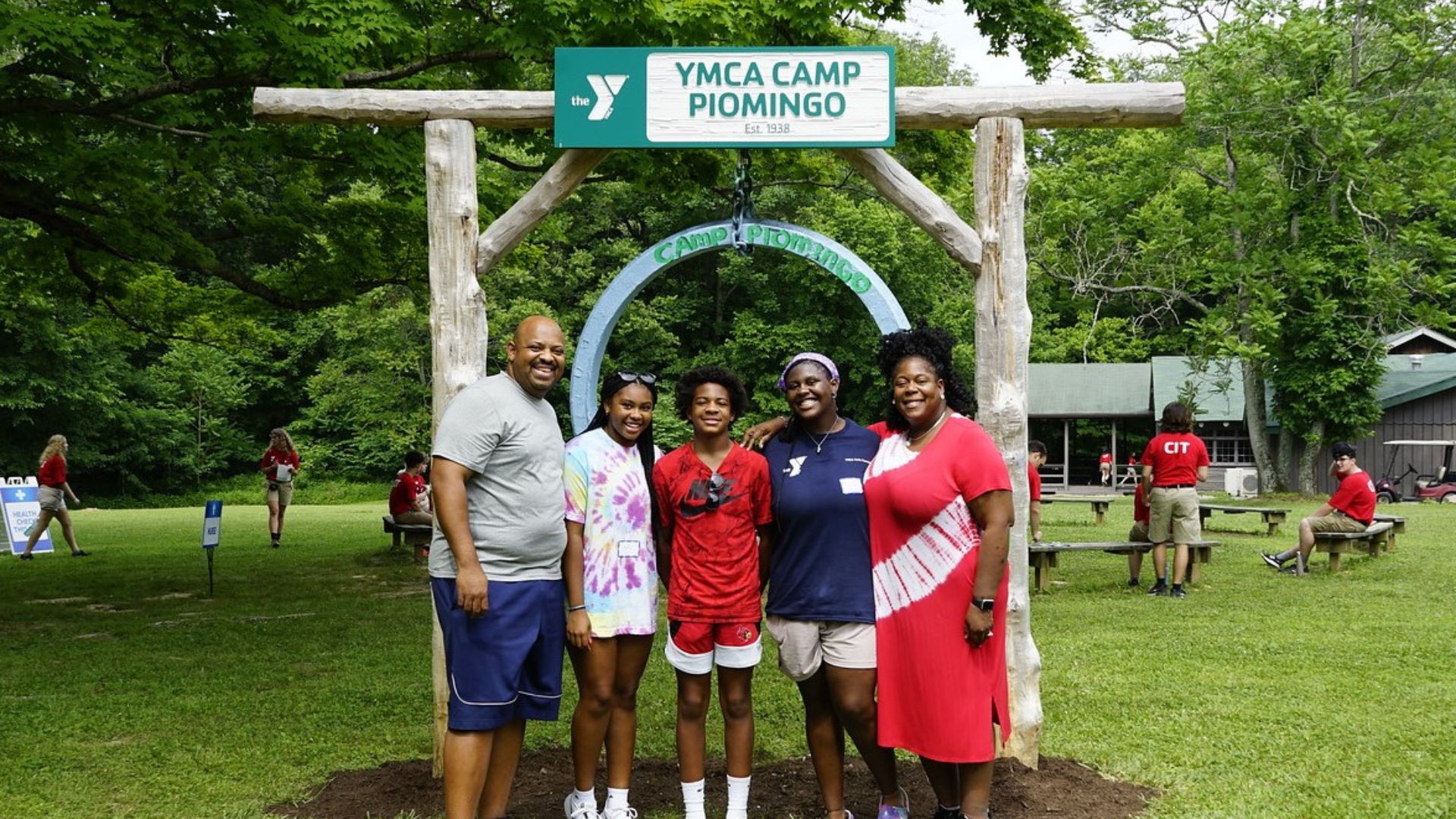 Family standing together in front of the YMCA Camp Piomingo gong Family standing together in front of the YMCA Camp Piomingo gong