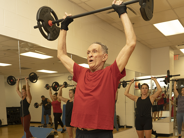 People with barbells in a YMCA strength group fitness class People with barbells in a YMCA strength group fitness class