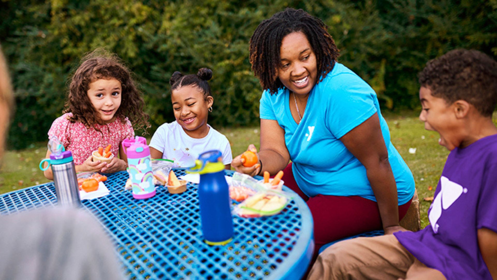 YMCA staff member outside with kids at YMCA summer camp YMCA staff member outside with kids at YMCA summer camp