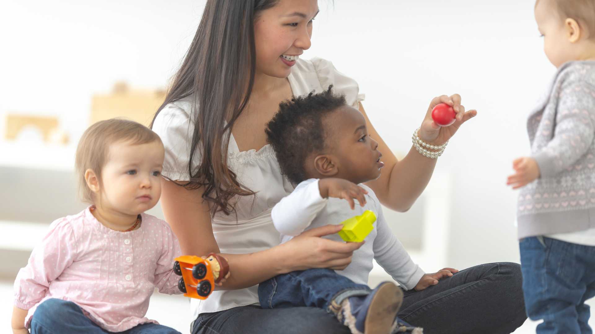 Adult with 3 young kids in a YMCA childcare program Adult with 3 young kids in a YMCA childcare program