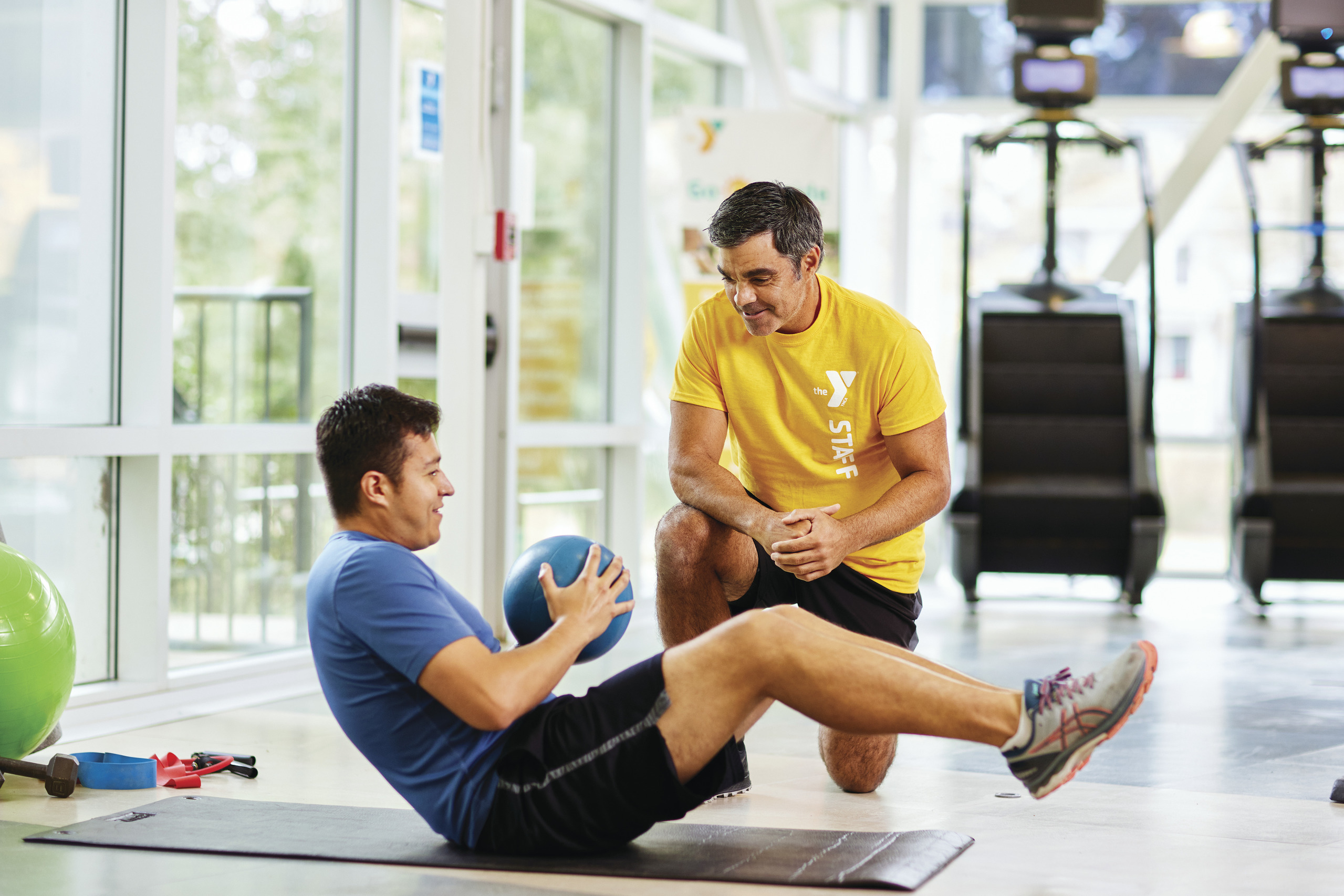 YMCA employee helping member exercise YMCA employee helping member exercise