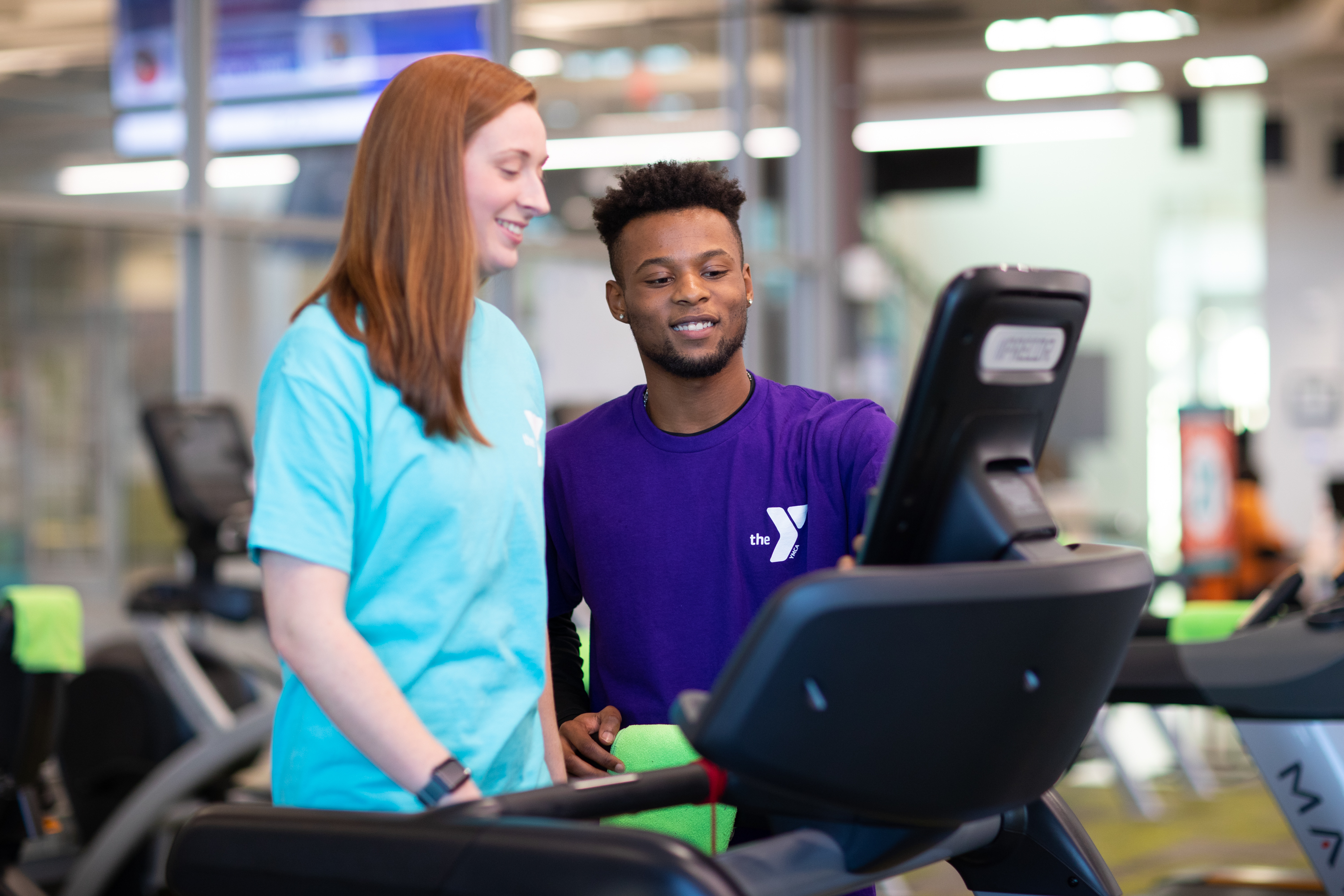 YMCA employee and member looking at treadmill screen YMCA employee and member looking at treadmill screen