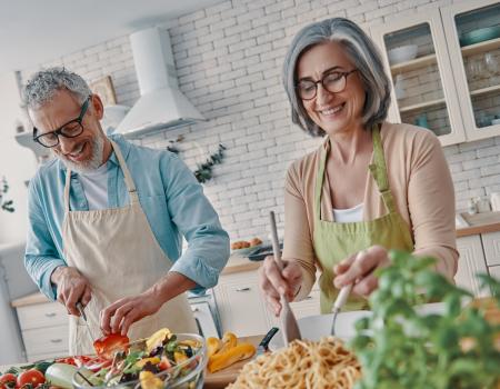 Older man and woman smiling and cooking a healthy meal at home Older man and woman smiling and cooking a healthy meal at home