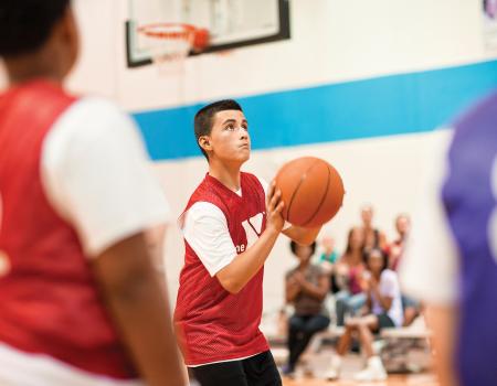 Kid shooting basketball during youth basketball league game Kid shooting basketball during youth basketball league game