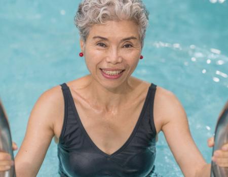 Smiling woman on ladder getting into pool Smiling woman on ladder getting into pool