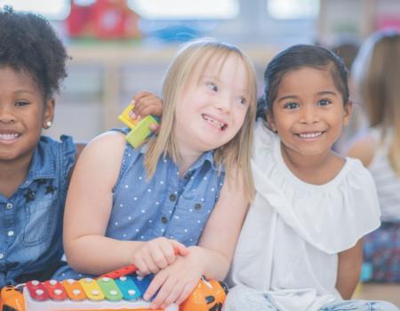 Three smiling young girls sitting and playing toy xylophone Three smiling young girls sitting and playing toy xylophone