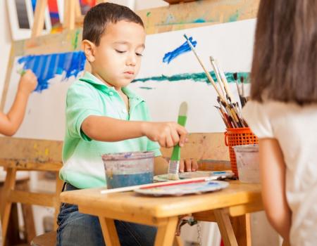 Young boy standing at a desk painting Young boy standing at a desk painting