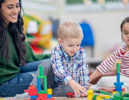 Adult with 3 young kids in a YMCA childcare program Adult with 3 young kids in a YMCA childcare program
