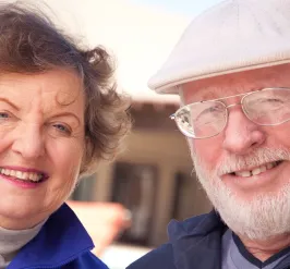 Smiling older man in hat and older woman outside together