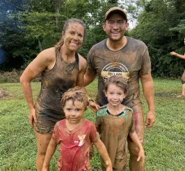 Smiling family covered in mud after completing the YMCA Mud Run
