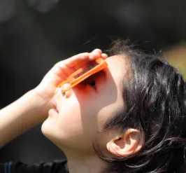 Girl looking up at an eclipse through a safety glass