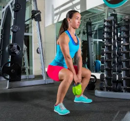 Young women squatting with a weight