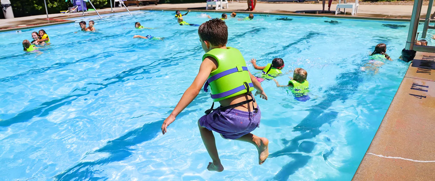 Child jumping into the pool at YMCA Camp Piomingo