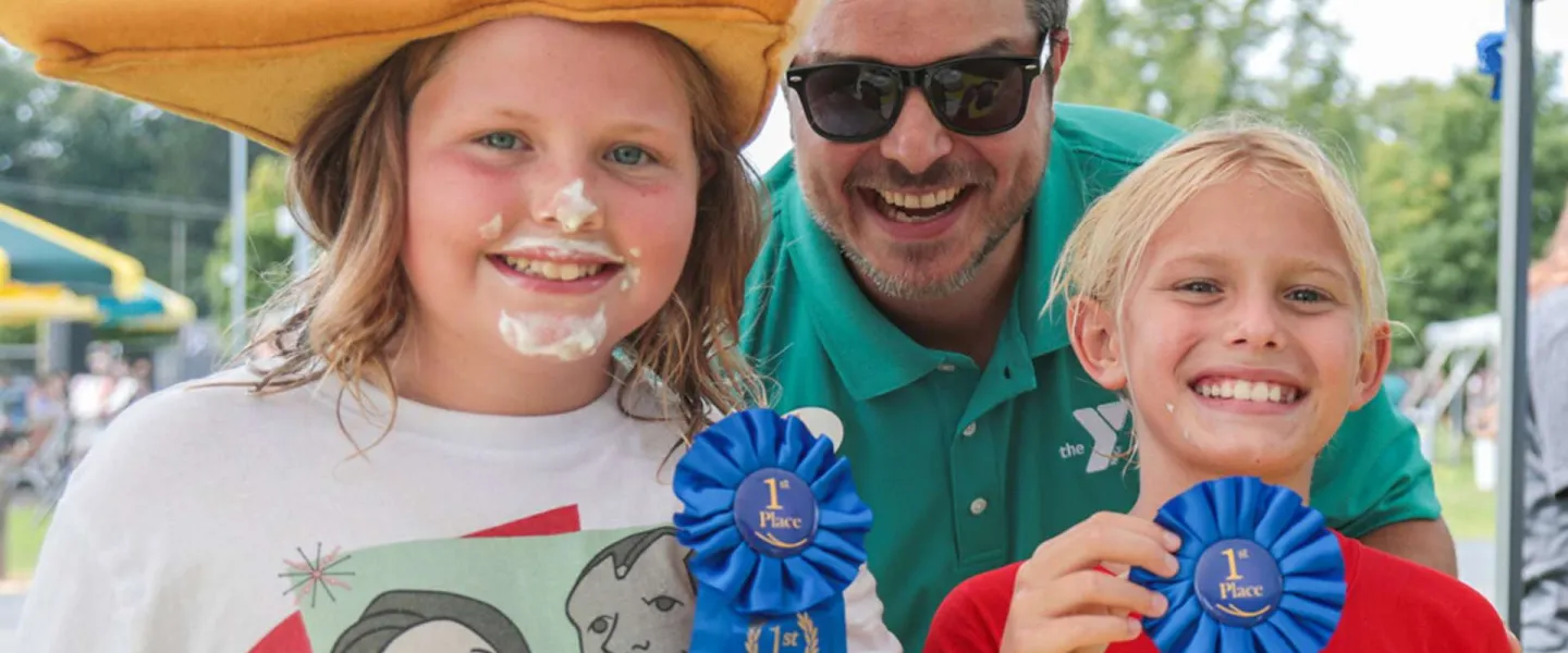 Two smiling children and a YMCA staff member at the YMCA family picnic