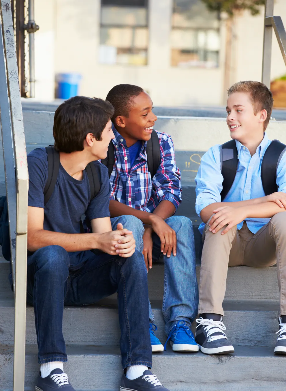 Three teens sitting on the steps after school, having a discussion