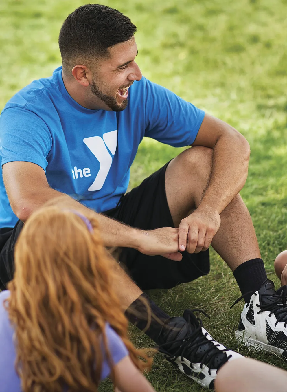 Group of smiling kids sitting outdoors with camp counselor
