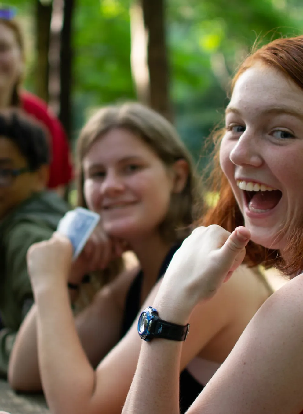 Kids hanging around a campfire, smiling for the camera