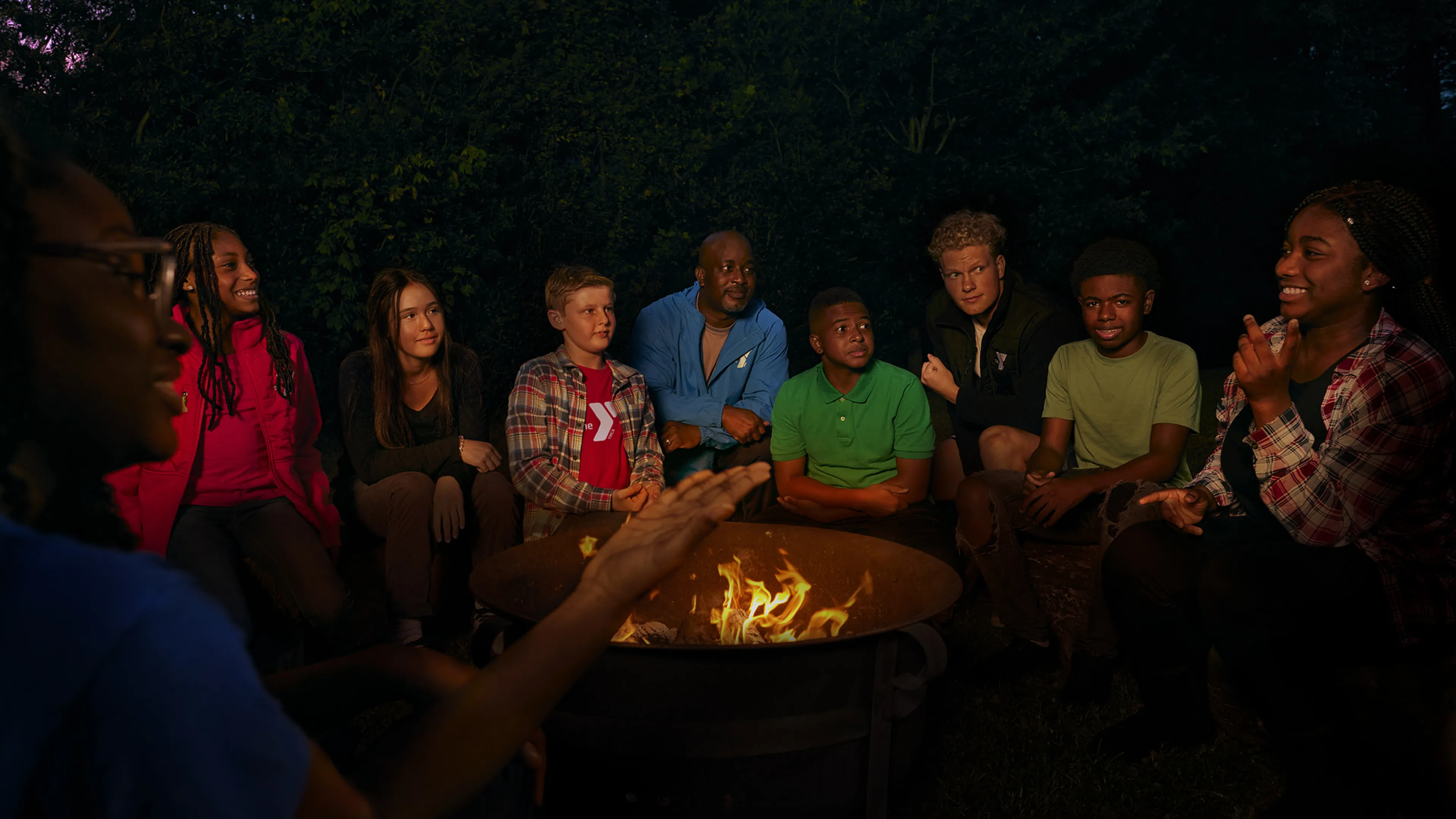 Children and camp counselors around campfire at YMCA Camp Piomingo