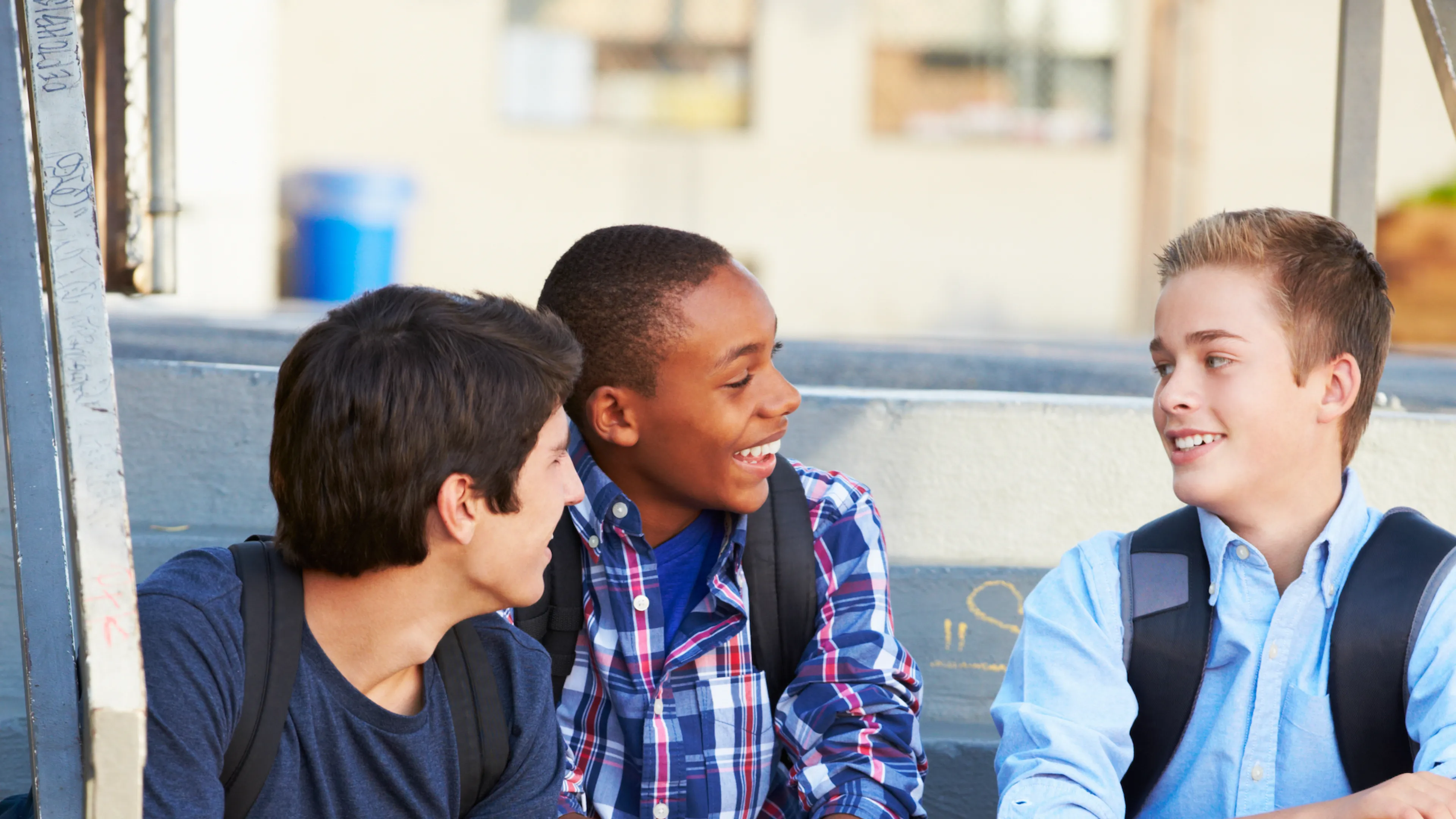 Three teens sitting on the steps after school, having a discussion