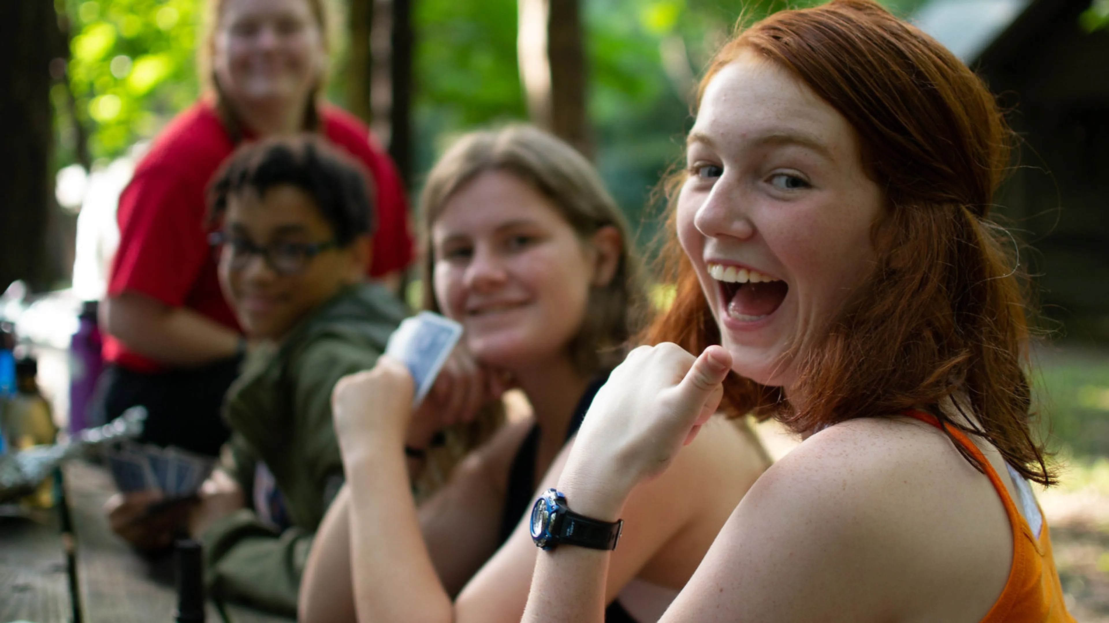 Kids hanging around a campfire, smiling for the camera