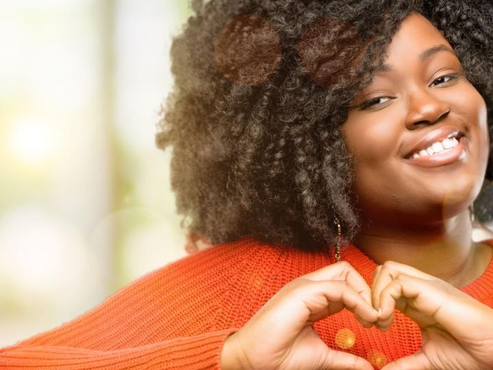 Smiling young woman making a heart with her hands
