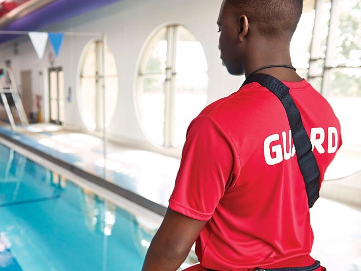 Male lifeguard watching over indoor pool