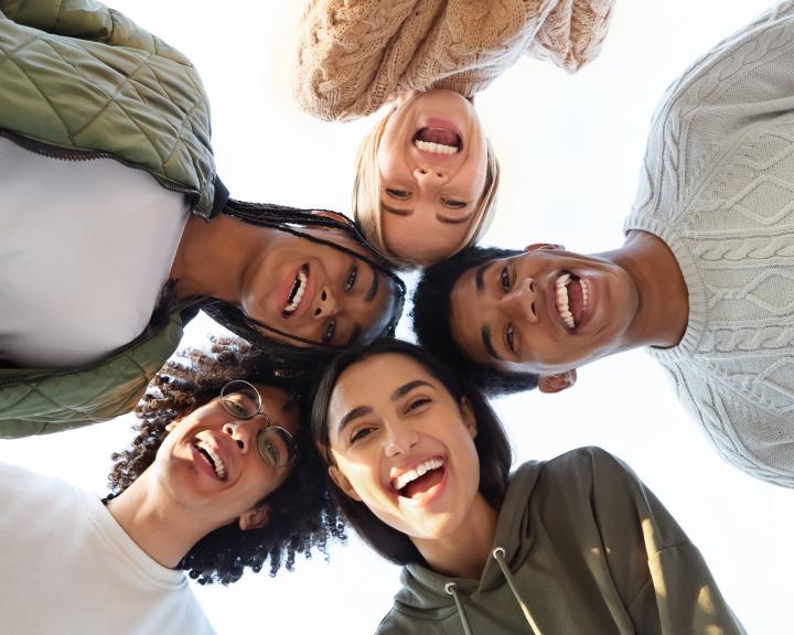 Five smiling teens standing in a circle, looking down at the camera Five smiling teens standing in a circle, looking down at the camera