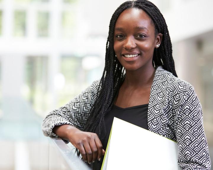Smiling African American teen learning against railing holding a notebook Smiling African American teen learning against railing holding a notebook
