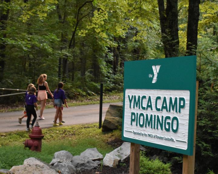 Campers walking past the YMCA Camp Piomingo welcome sign Campers walking past the YMCA Camp Piomingo welcome sign