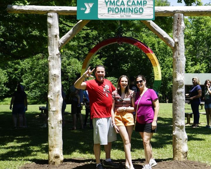 Family standing together in front of the YMCA Camp Piomingo gong Family standing together in front of the YMCA Camp Piomingo gong