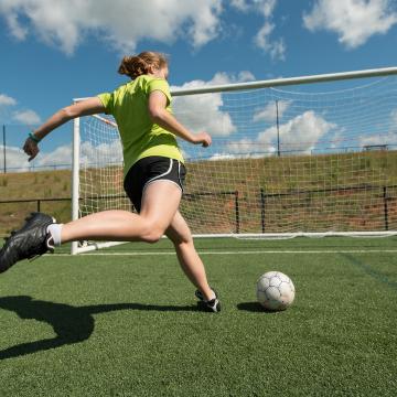 Woman kicking soccer ball in YMCA Louisville's adult soccer league Woman kicking soccer ball in YMCA Louisville's adult soccer league
