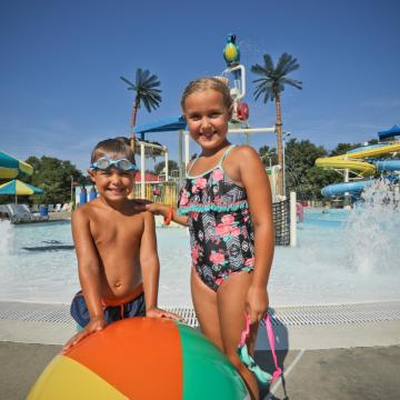 Three kids posing in front of Calypso Cove Waterpark interactive play structure Three kids posing in front of Calypso Cove Waterpark interactive play structure