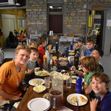 Kids and teens gathered around a table eating a meal at Camp Piomingo Kids and teens gathered around a table eating a meal at Camp Piomingo